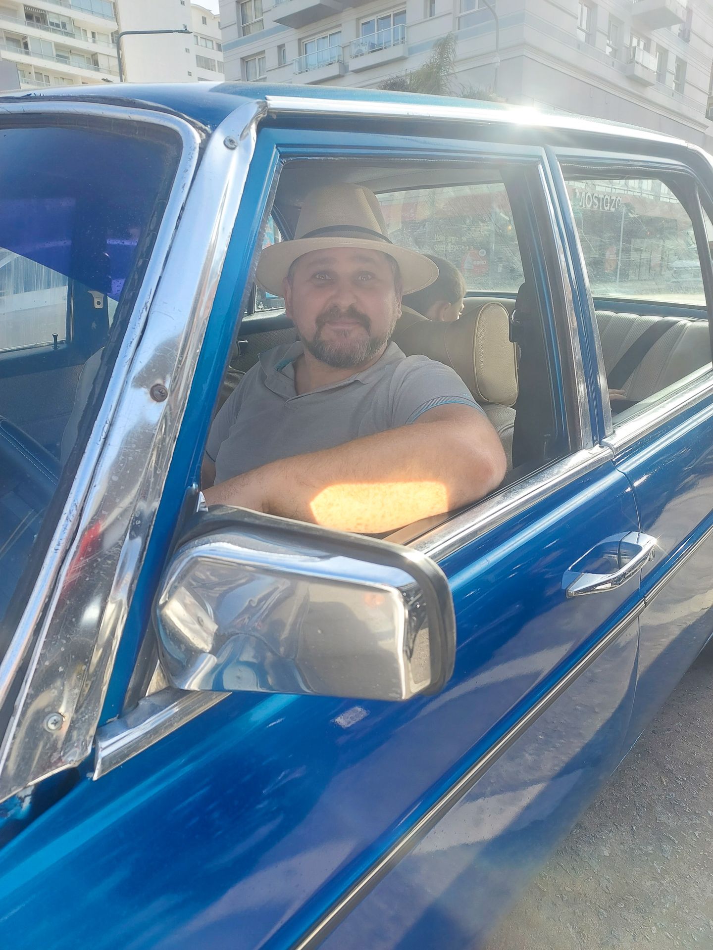 Man wearing a hat inside a blue classic vintage car in Uruguay